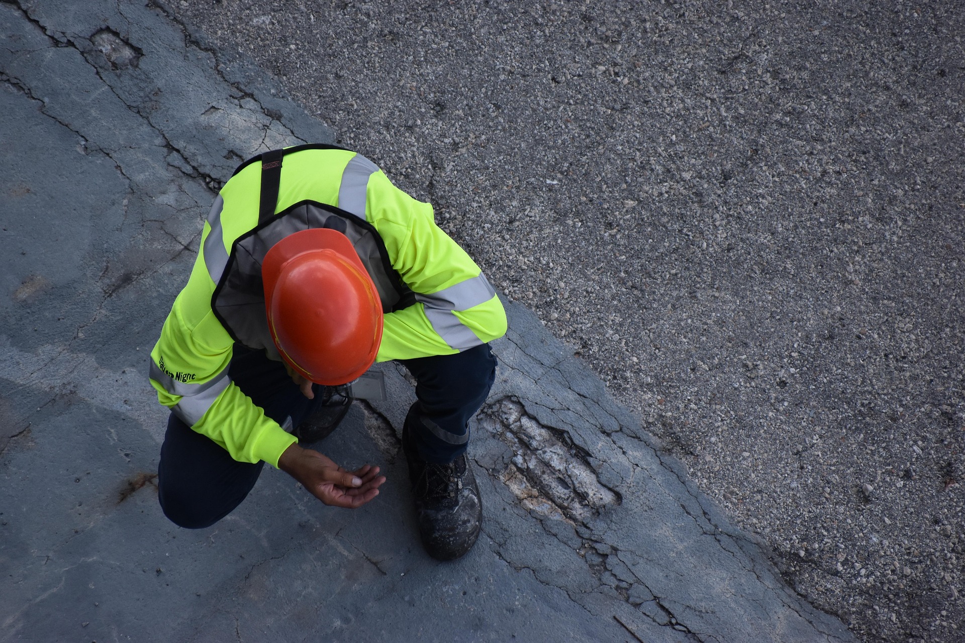 Road worker inspecting pavement